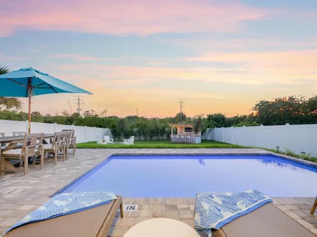 a view of swimming pool with a table and chairs under an umbrella