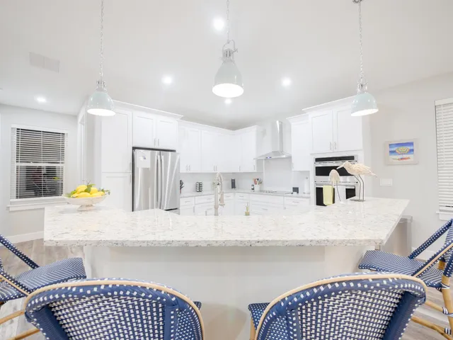 a kitchen with stainless steel appliances granite countertop a refrigerator a sink dishwasher a dining table and chairs with wooden floor