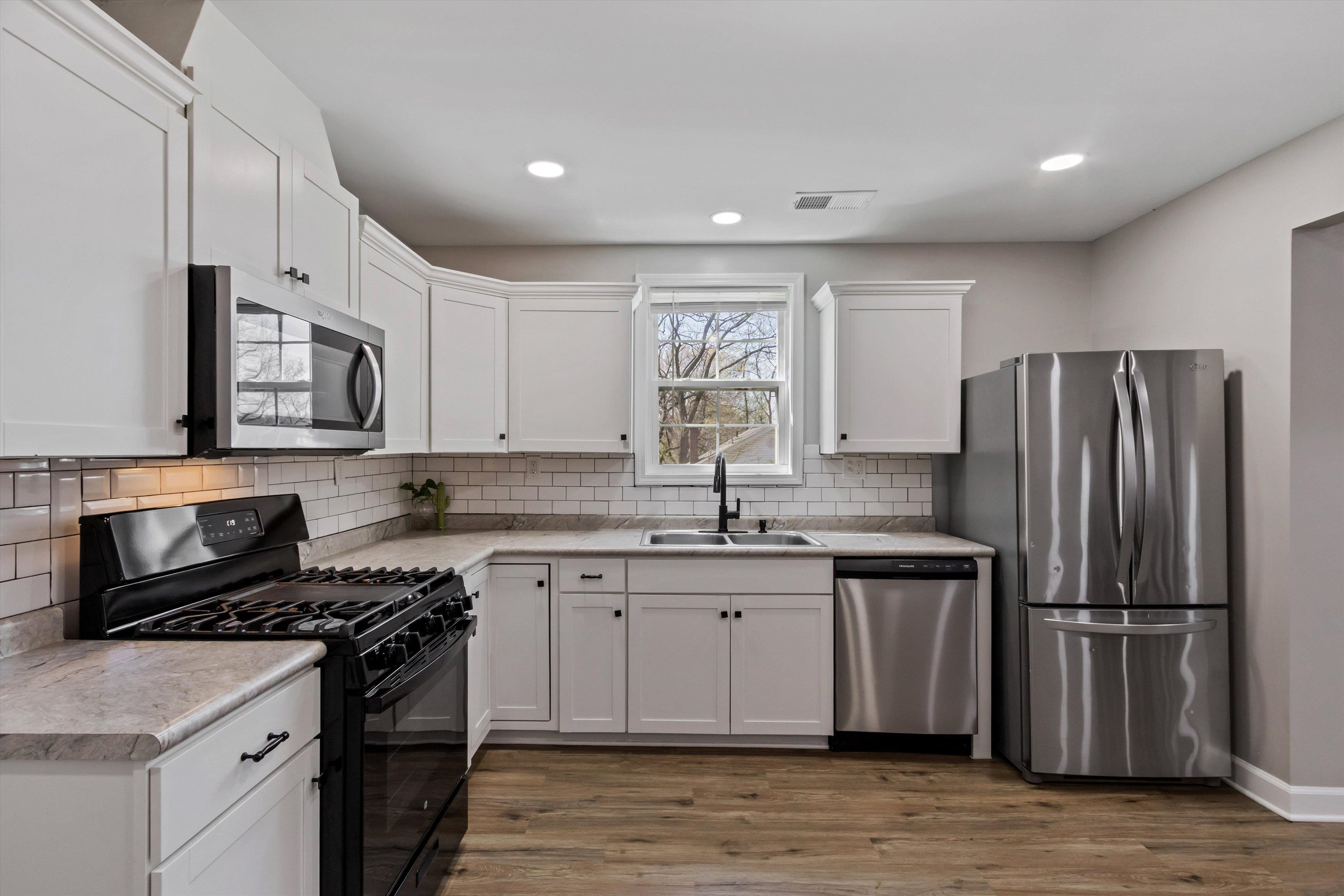 1217 Carlton Road Memphis, TN 38106 - Photo 11 of 32 Kitchen featuring stainless steel appliances, light countertops, white cabinets, light wood finished floors, and recessed lighting