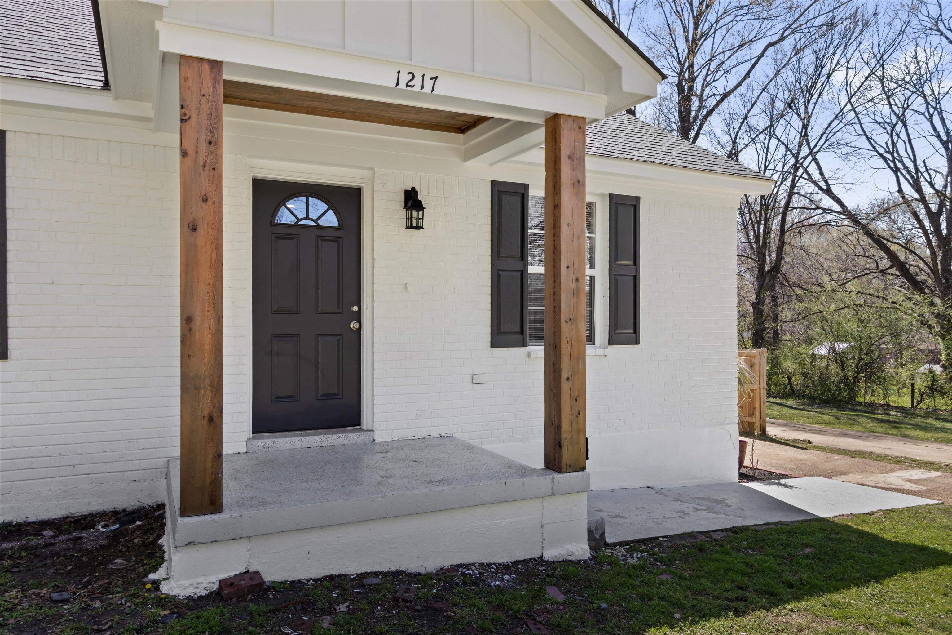 1217 Carlton Road Memphis, TN 38106 - Photo 3 of 32 Doorway to property with brick siding, covered porch, and roof with shingles