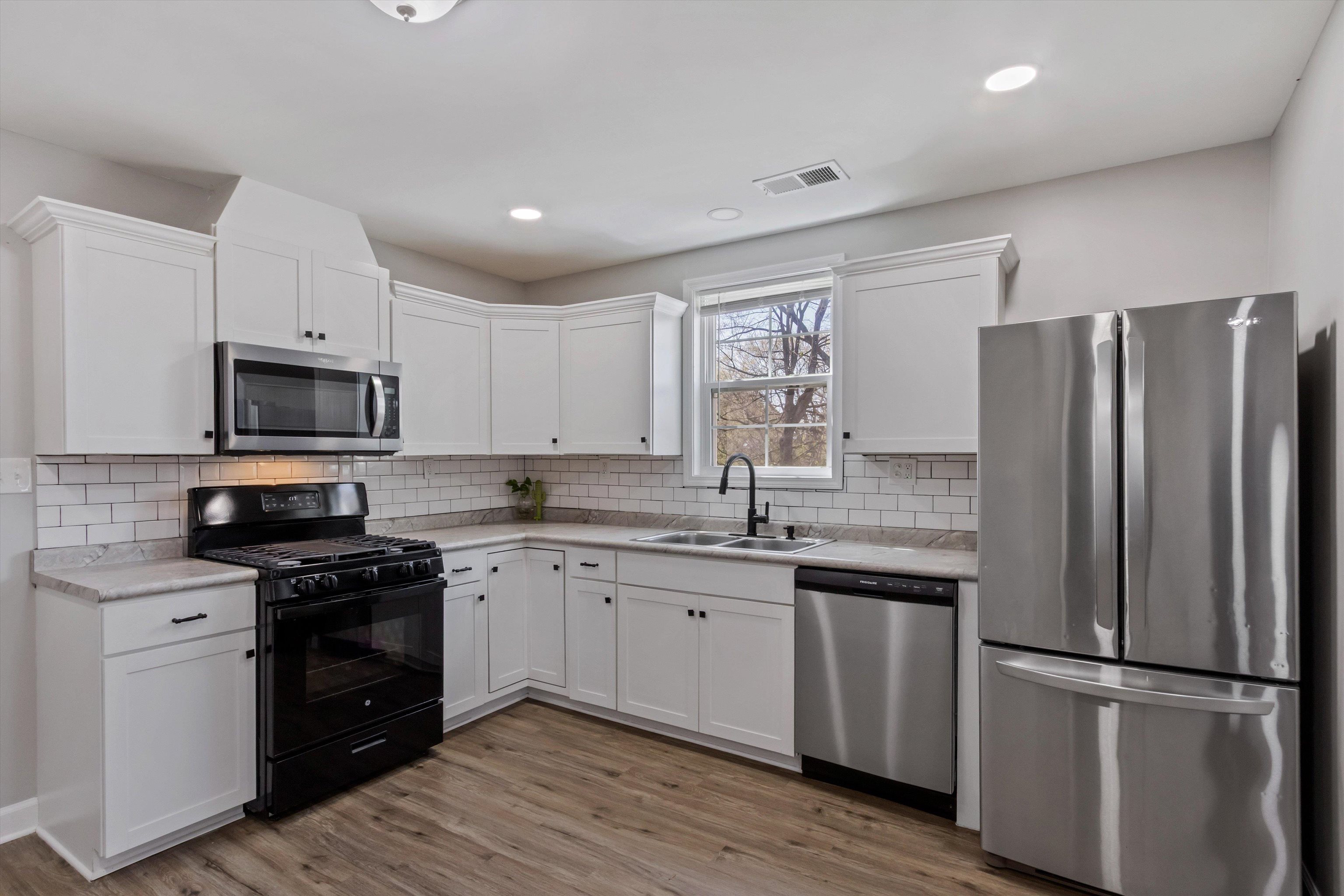 1217 Carlton Road Memphis, TN 38106 - Photo 9 of 32 Kitchen featuring stainless steel appliances, white cabinets, light countertops, light wood-style floors, and recessed lighting
