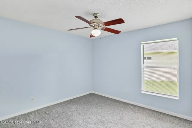 an empty room with ceiling fan and window