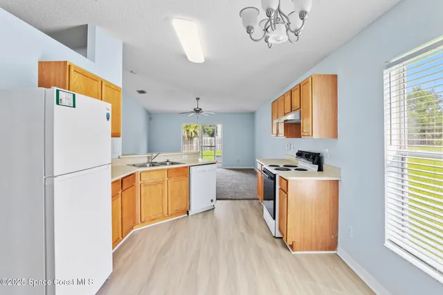 a kitchen with stainless steel appliances granite countertop a refrigerator a stove a sink dishwasher and a dining table with wooden floor