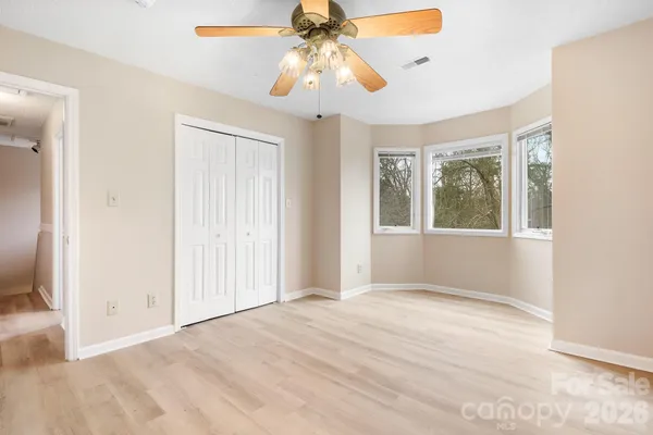 an empty room with chandelier fan and windows