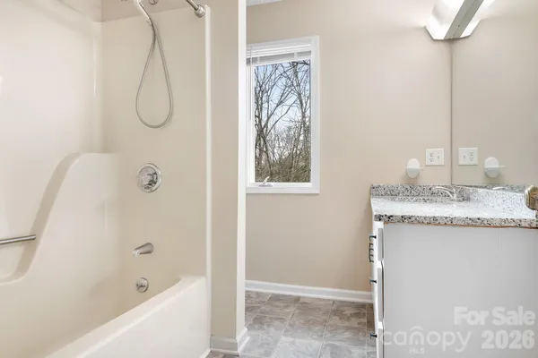 a bathroom with a granite countertop sink a mirror and a bathtub