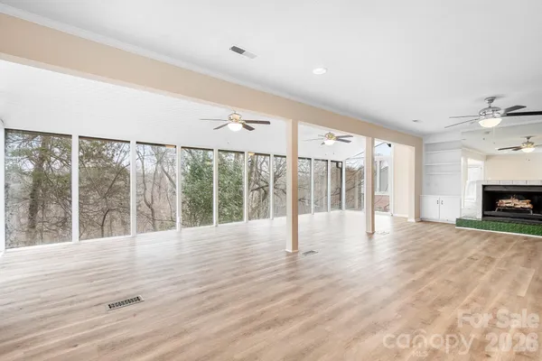 a view of an empty room with wooden floor and a fireplace