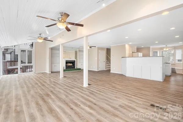 a view of a living room with wooden floor and a kitchen space