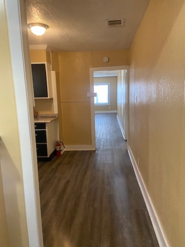 214 South Hackberry Avenue Luling, TX 78648 - Photo 5 of 22 Hall with dark wood-type flooring, a textured wall, and a textured ceiling