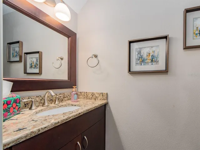 a bathroom with a granite countertop sink a mirror and a picture of bathroom