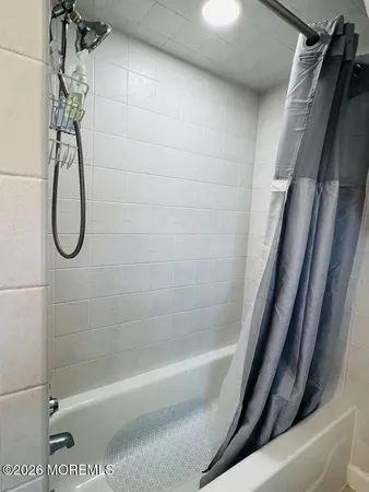 a bathroom with a shower and white bath tub