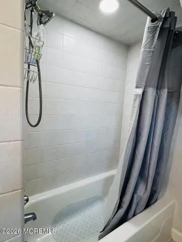 a bathroom with a shower and white bath tub