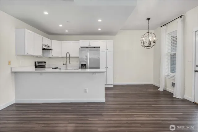 a view of kitchen cabinets wooden floor stainless steel appliances and cabinets