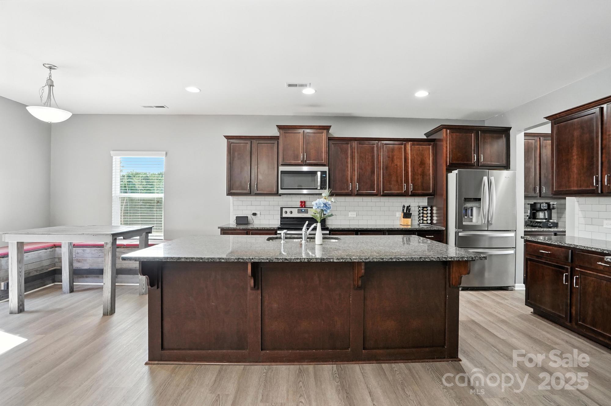 6405 Fawn Crest Drive Waxhaw, NC 28173 - Photo 5 of 38 a kitchen with stainless steel appliances granite countertop wooden cabinets a sink dishwasher a stove and a refrigerator with wooden floor