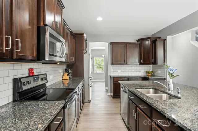 a kitchen with stainless steel appliances granite countertop a sink stove and refrigerator