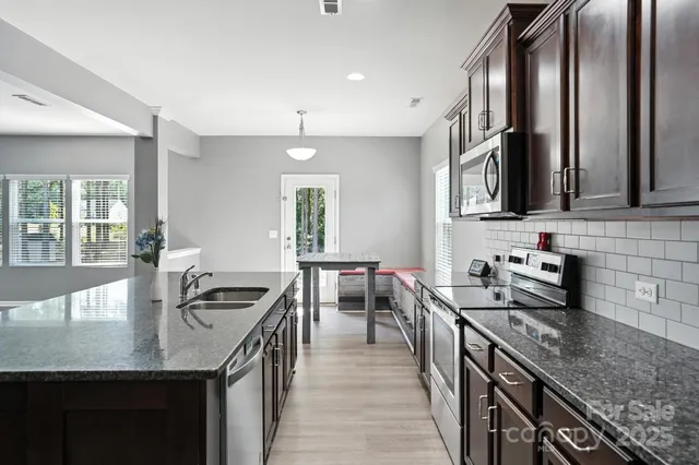 a kitchen with stainless steel appliances granite countertop a sink a stove and a wooden floors