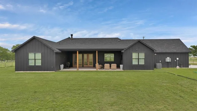 a view of a brick house with a big yard and large trees