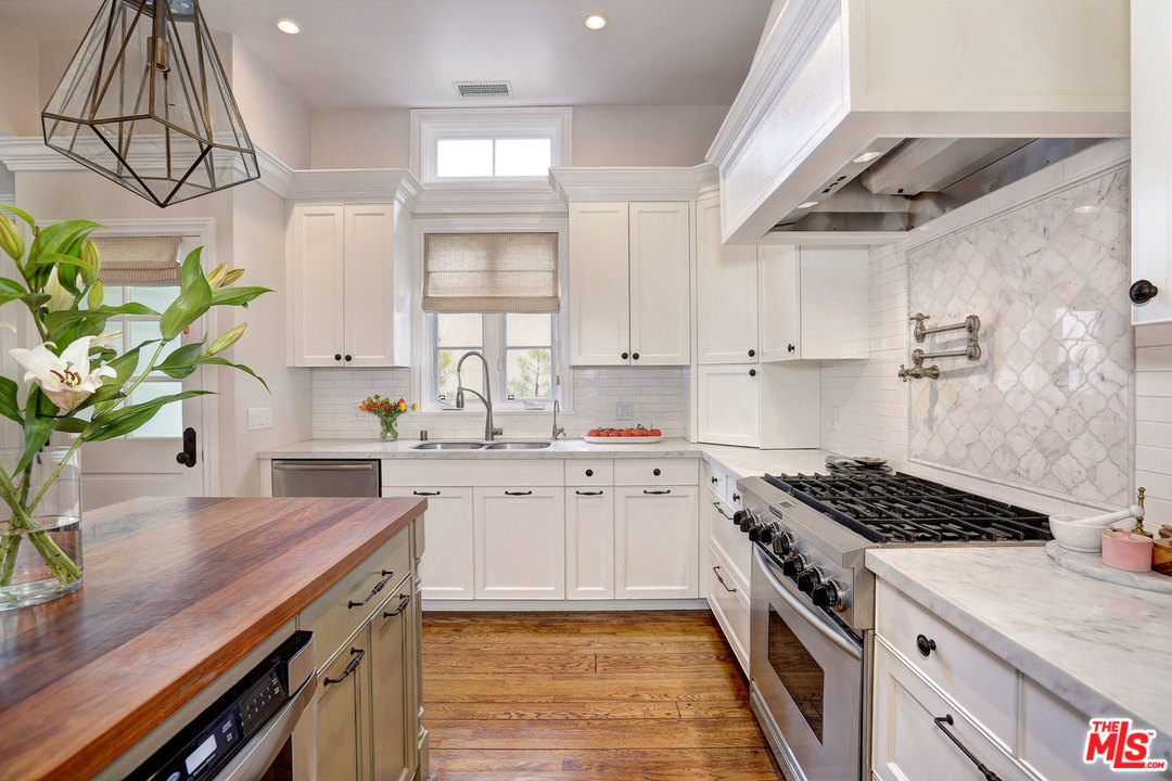 a kitchen with stainless steel appliances a sink a stove cabinets counter space and a window