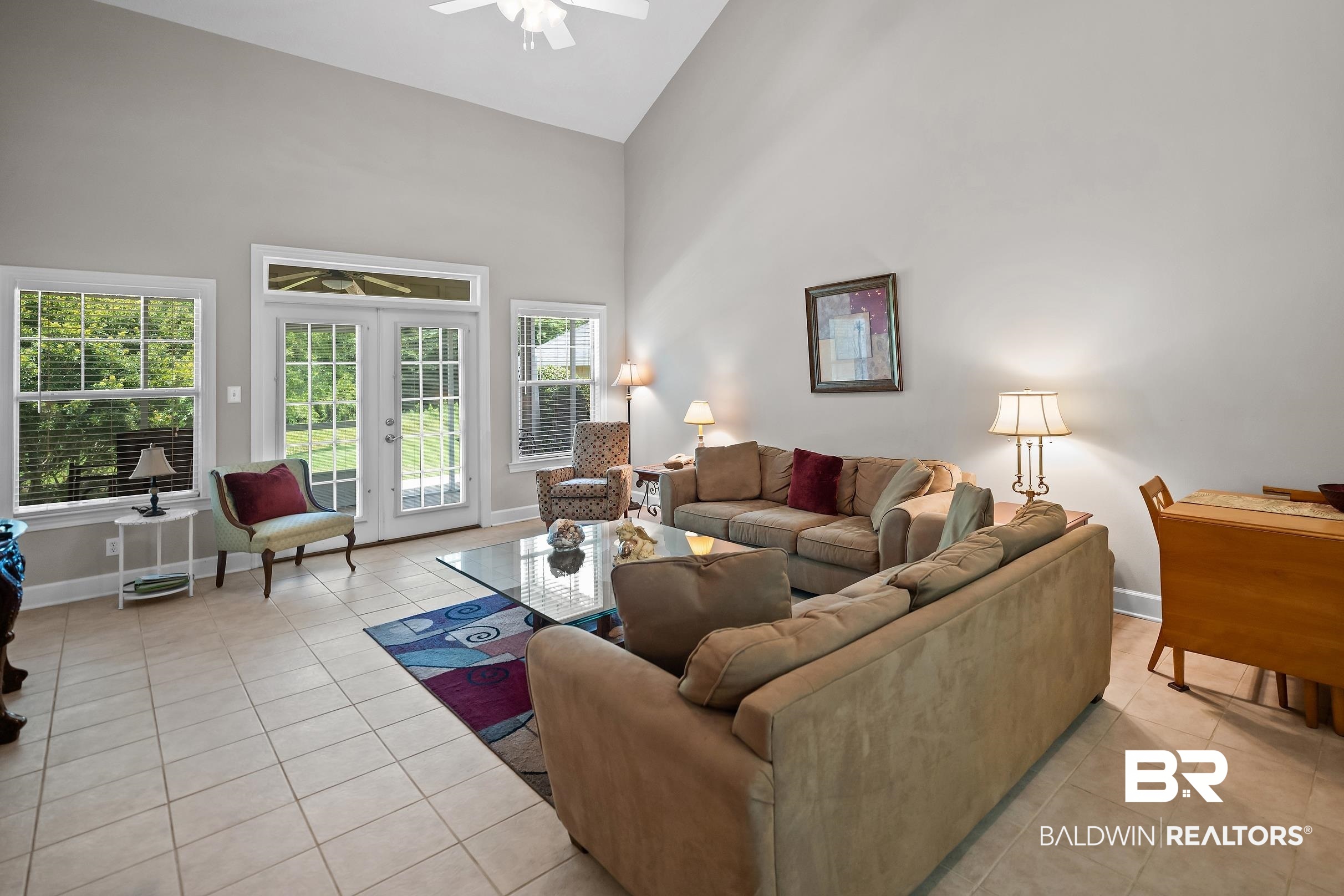 430 West Fort Morgan Road, Unit 704 Gulf Shores, AL 36542 - Photo 4 of 35 Expansive living area featuring a vaulted ceiling with a ceiling fan, light gray painted walls, and tile flooring