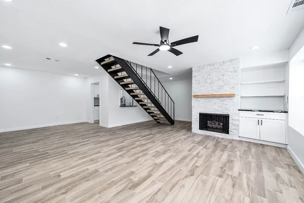 an empty room with wooden floor fireplace and windows