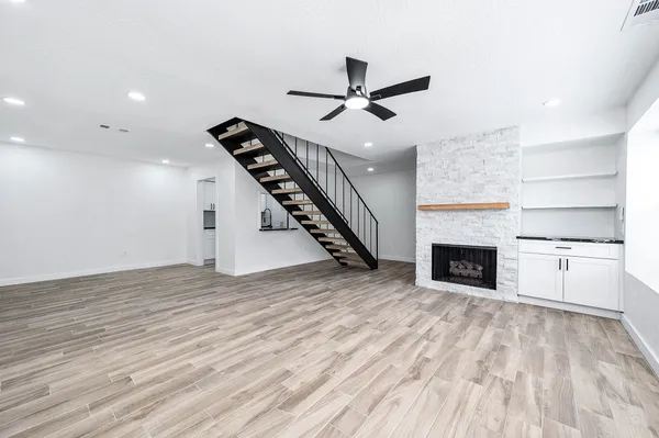 an empty room with wooden floor fireplace and windows