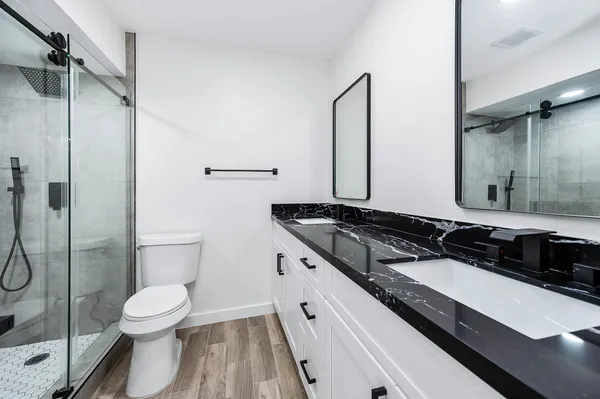 a bathroom with a granite countertop sink toilet a mirror and shower