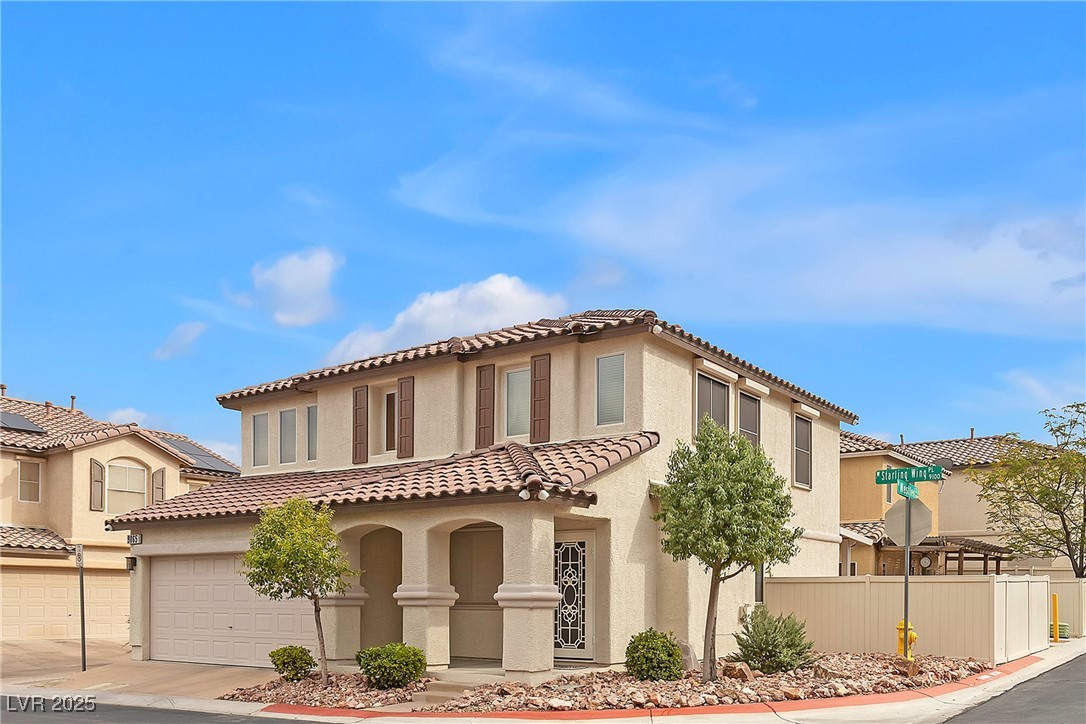9065 Starling Wing Place Las Vegas, NV 89143 - Photo 2 of 53 Mediterranean / spanish-style house featuring a garage, stucco siding, driveway, and a tile roof