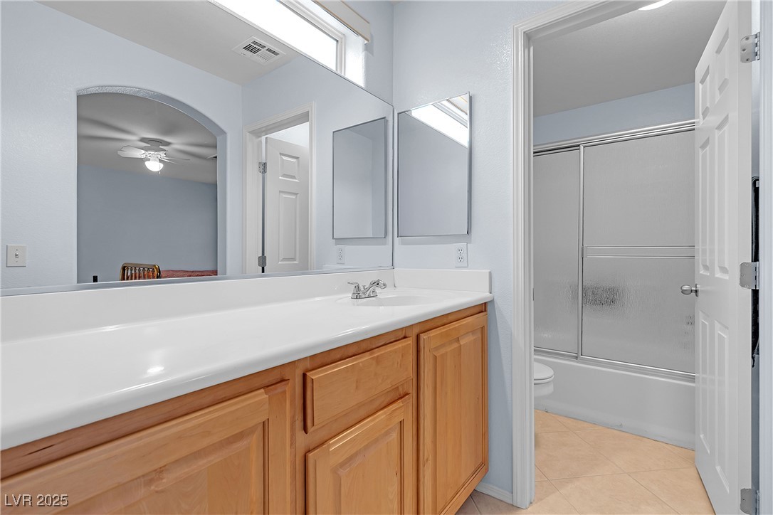 9065 Starling Wing Place Las Vegas, NV 89143 - Photo 29 of 53 Bathroom featuring vanity, shower / bath combination with glass door, light tile patterned flooring, and a ceiling fan