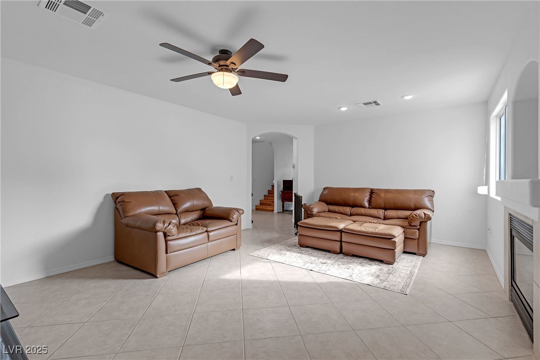 9065 Starling Wing Place Las Vegas, NV 89143 - Photo 4 of 53 Living area with arched walkways, stairway, a glass covered fireplace, light tile patterned floors, and ceiling fan