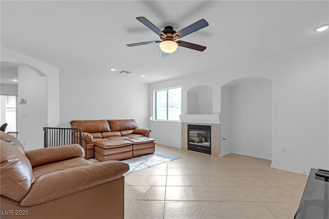 9065 Starling Wing Place Las Vegas, NV 89143 - Photo 5 of 53 Living room with arched walkways, light tile patterned floors, a tiled fireplace, a ceiling fan, and recessed lighting