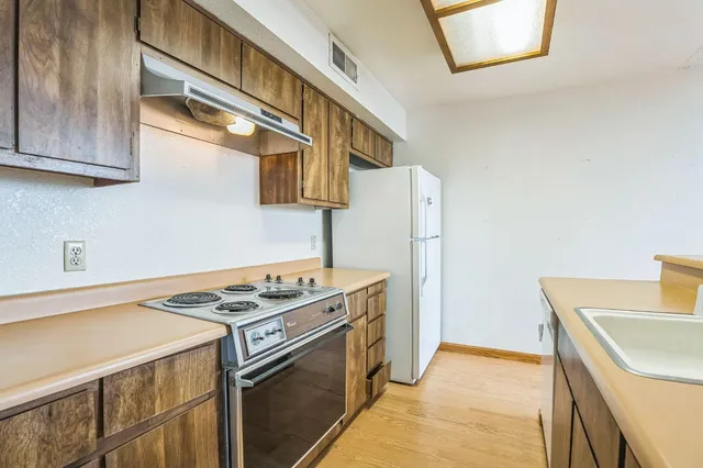 a kitchen with stainless steel appliances granite countertop a sink a stove and a refrigerator
