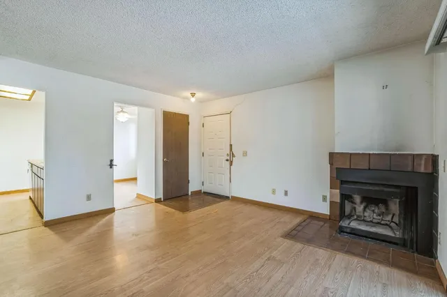 a view of empty room with wooden floor and fireplace