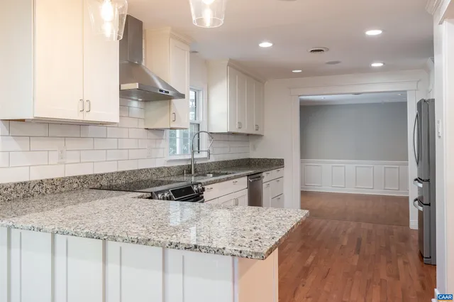 a kitchen with granite countertop a sink a stove and cabinets