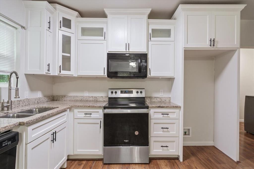3109 North 20th Street Waco, TX 76708 - Photo 10 of 24 Well-appointed kitchen featuring white cabinetry with dark hardware, speckled countertops, a double basin stainless steel sink with a gooseneck faucet, and wood-finish flooring