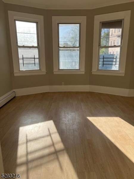 a view of wooden floor in an empty room with a window