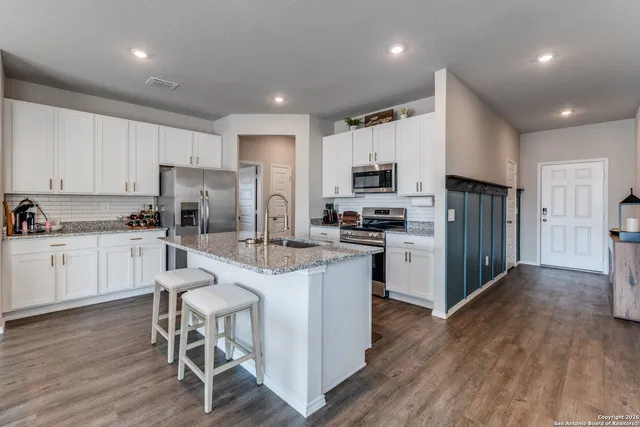 a kitchen with kitchen island white cabinets and stainless steel appliances