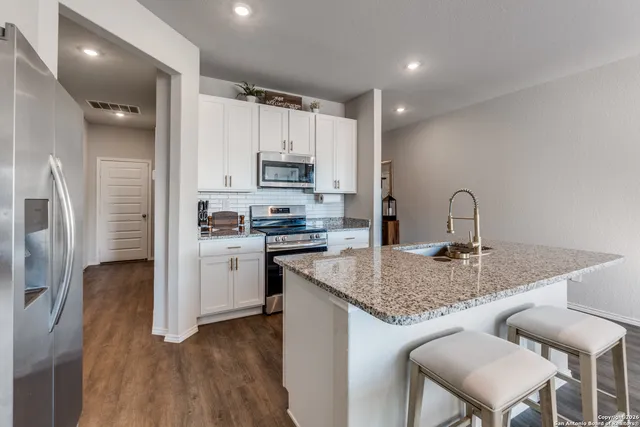 a kitchen with kitchen island granite countertop a sink cabinets and stainless steel appliances