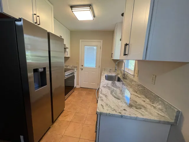 a kitchen with granite countertop a refrigerator and a sink
