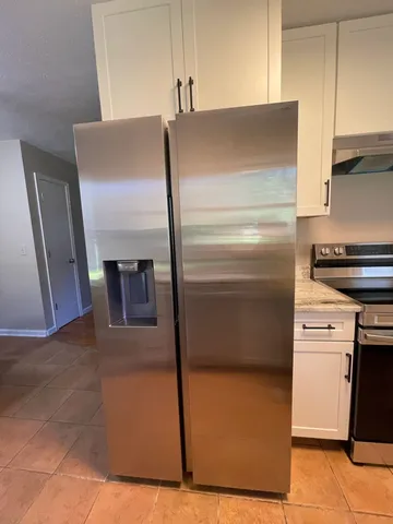 a view of a refrigerator in kitchen and an empty room