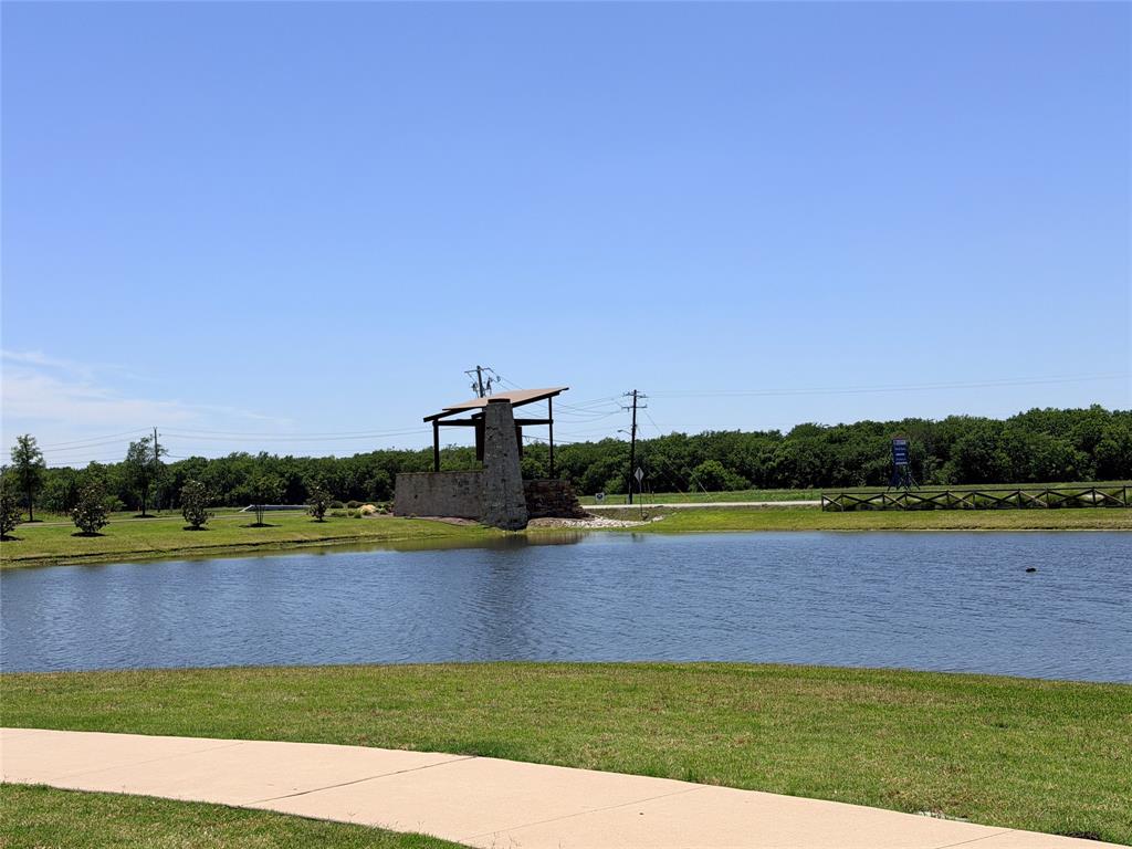 816 Country Road Royse City, TX 75189 - Photo 19 of 24 Water feature with a stone structure, framed by green space and a treeline