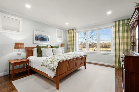 a bedroom with a bed lamp and a large window