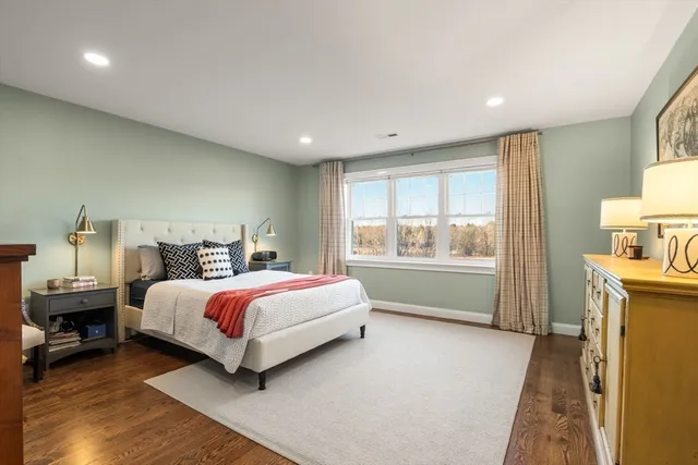 a spacious bedroom with a bed and wooden floor