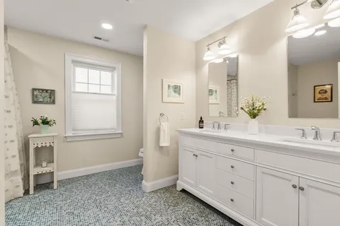 a spacious bathroom with a double vanity sink a mirror a bathtub and window