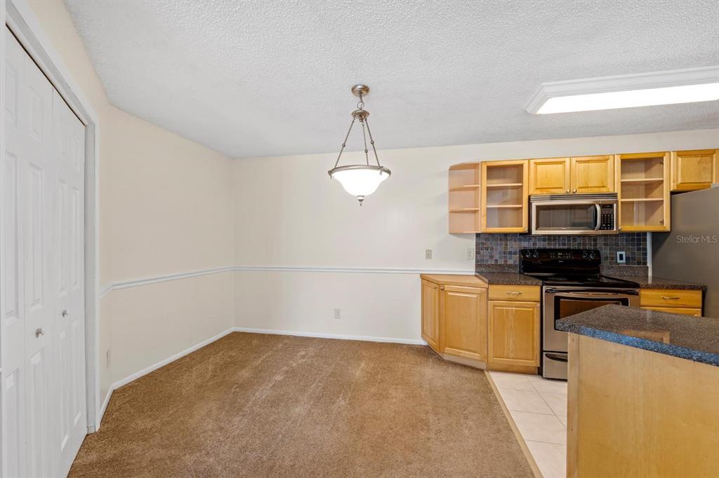 1550 South Belcher Road, Unit 223 Clearwater, FL 33764 - Photo 8 of 38 a kitchen with stainless steel appliances a stove a refrigerator a sink dishwasher with a dining table and chairs