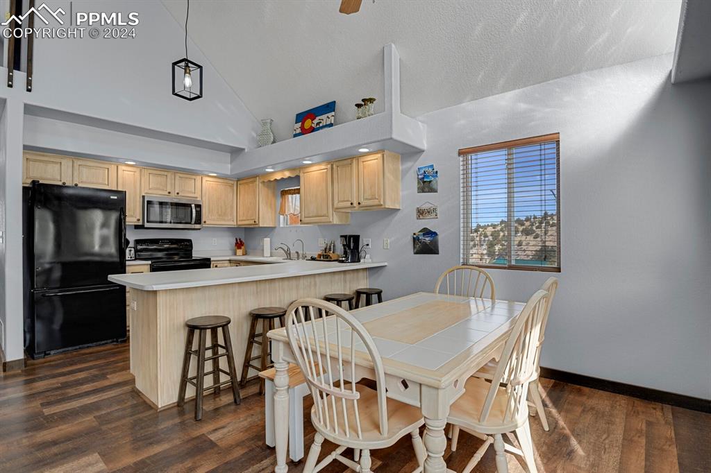 998 Bunker Hill Road Silver Cliff, CO 81252 - Photo 17 of 49 a kitchen with stainless steel appliances granite countertop a stove a refrigerator a kitchen island a dining table and chairs with wooden floor