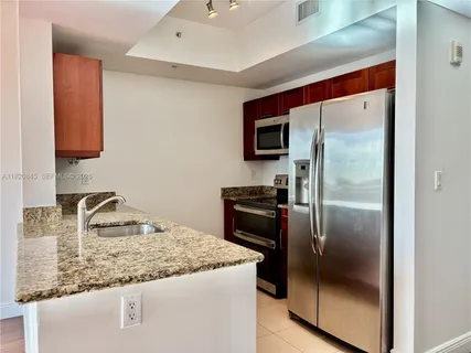 a kitchen with granite countertop a refrigerator and a sink