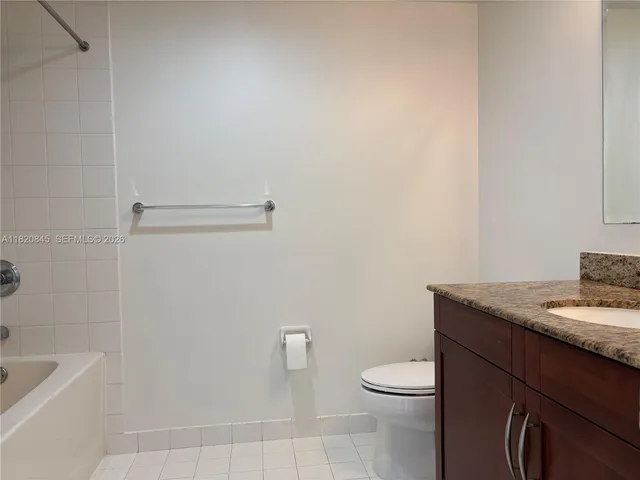 a bathroom with a granite countertop toilet and a sink