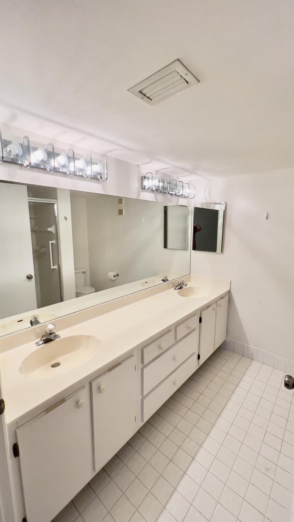 6121 Pointe Regal Circle, Unit 209 Delray Beach, FL 33484 - Photo 16 of 41 a spacious bathroom with a double vanity sink and mirror