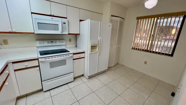 a kitchen with white cabinets and white appliances