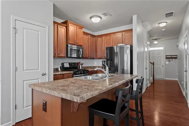a kitchen with stainless steel appliances granite countertop a table chairs refrigerator and sink