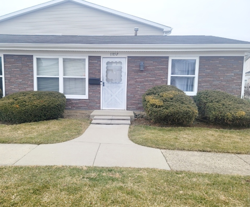 1315 Kingsbury Drive, Unit F Hanover Park, IL 60133 - Photo 1 of 2 a view of a brick house with plants
